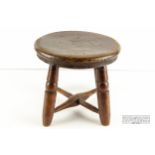 A low legged oak stool with round seat and X-stretcher