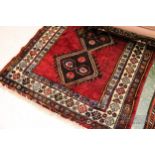 An Iranian rug, handmade, the burgundy ground with four square motifs through the central field