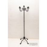 A wrought iron four-branch candle stand, on four feet, 156cm high approx.