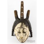 An African ceremonial sprit or Mwo mask, the carved wood painted in black and white, modelled as a