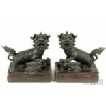 A pair of Chinese bronze dogs of fo, seated with one paw raised on a flaming pearl, on flat