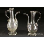 A pair of colourless glass wet condiment ewers, 19th century, 15cm high approx. and smaller (2)