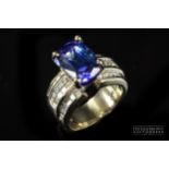 A tanzanite and diamond dress ring, the oval mixed cut tanzanite weighing approximately 6ct, of