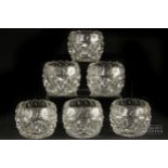 A set of six cut glass salts, squat barrel form cut with diamond banding beneath faceted scalloped