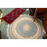 A round floral rug, cream ground with central medallion surrounded by flowers on a blue ground,