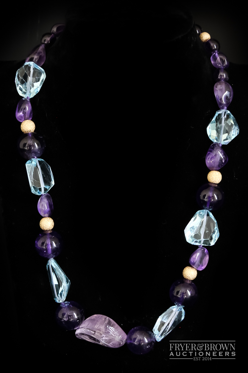 A blue topaz and amethyst bead necklace, the graduated necklace set with 29 polished amethyst and