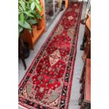 A very long Iranian runner rug, wool, the red ground with various guls and floral borders, 642 x