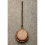 A copper long handled bed warmer