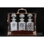 A silver plated tantalus, enclosing three decanters with ball stoppers, 32.5cm high max. approx.