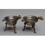 TWO TRIPOD VESSELS WITH HANDLE AND SPOUT  Silver and gilding. China, presumably Six Dynasties period