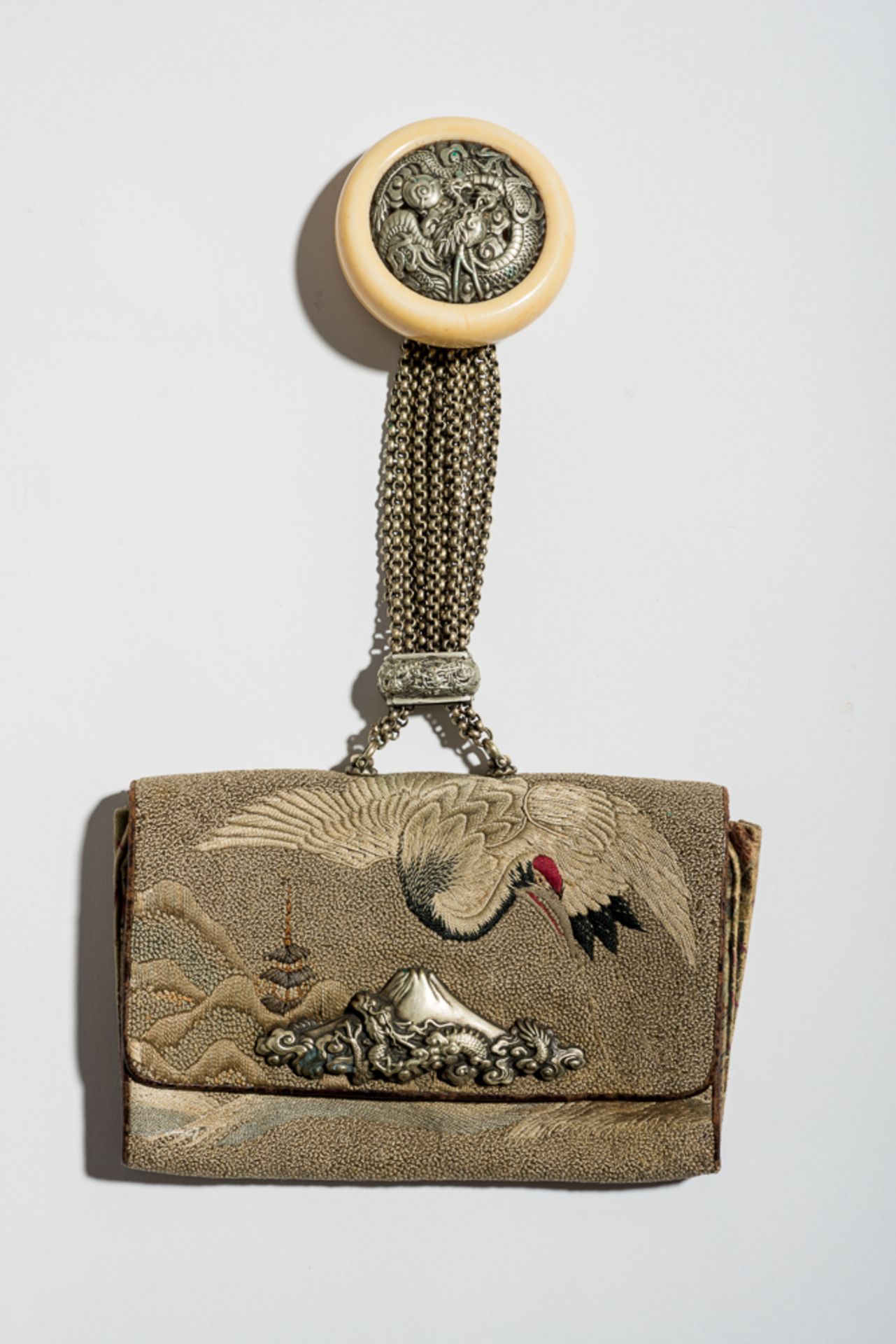 GELDTASCHE KINCHAKU UND DRACHEN-NETSUKE
Elfenbein, Silber und Seidenbrokat. Japan, 19. Jh.Ein