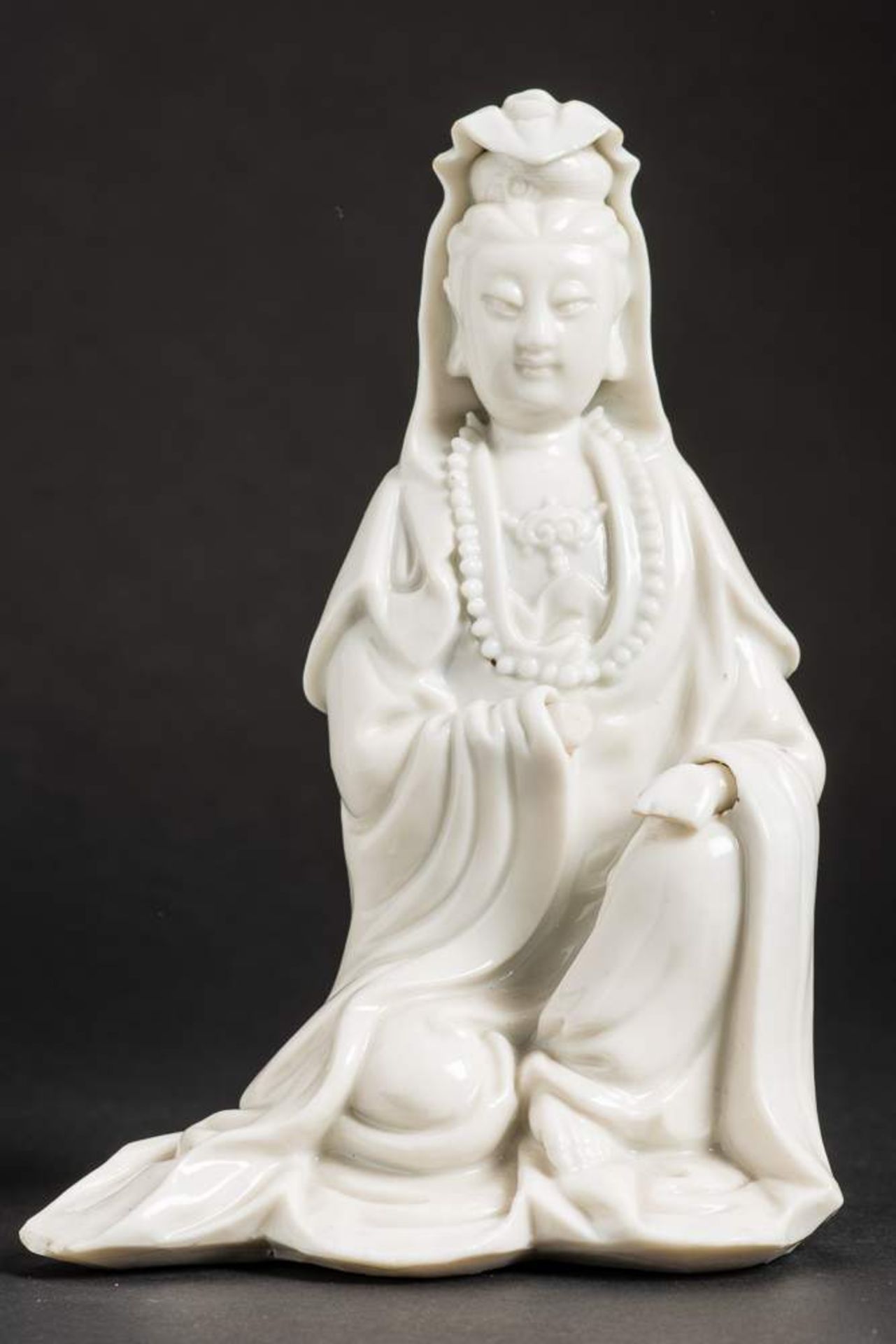 SITZENDE GUANYIN
Blanc de Chine-Porzellan. China, späte Qing-Dynastie, ca. 19. Jh.Die