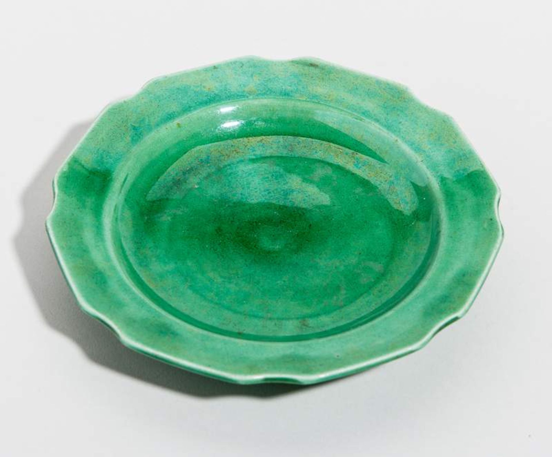 KLEINER TELLER
Grün glasiertes Porzellan. China, Qing-Dynastie, 19. Jh.Oktogonaler Rand, jeweils