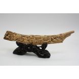 A carved ivory tusk, on carved wooden stand, depicting birds in a townscape, 32cm long