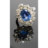 An 18ct white gold, sapphire and diamond cluster ring, the central oval-cut sapphire approx 4.