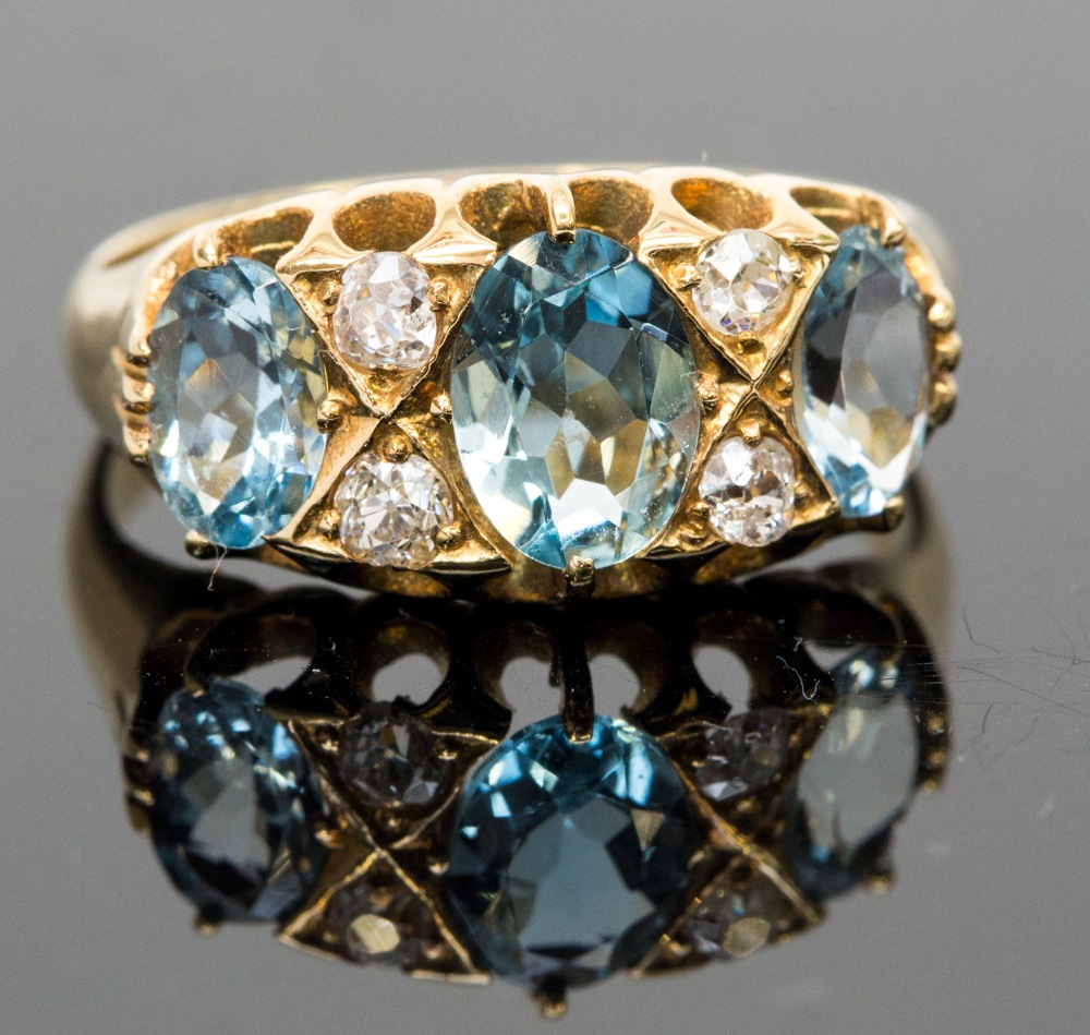 An 18ct gold aquamarine and diamond ring, set with three graduated oval-cut aquas, divided by four