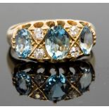 An 18ct gold aquamarine and diamond ring, set with three graduated oval-cut aquas, divided by four