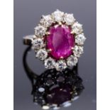 An 18ct gold, ruby and diamond cluster ring, set with an oval cut ruby, surrounded by twelve round