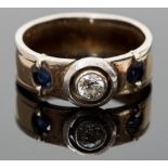 A diamond and sapphire ring, set with a central diamond flanked by sapphires to shank, ring size