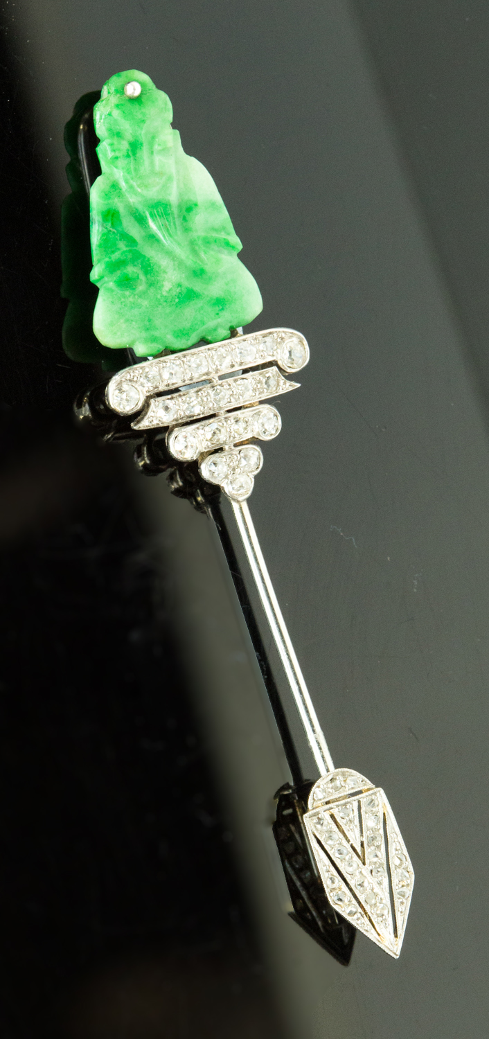 An Art Deco jadeite and diamond jabot stick pin, carved figure seated above four rows of diamonds,