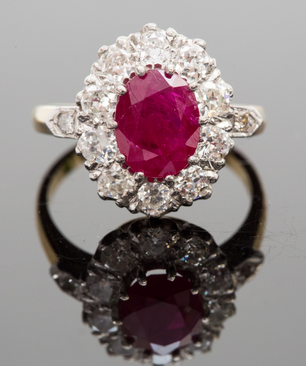 An 18ct gold, ruby and diamond cluster ring, the central oval-cut ruby approx 2.20cts, surrounded by