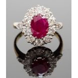 An 18ct gold, ruby and diamond cluster ring, the central oval-cut ruby approx 2.20cts, surrounded by