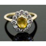 An 18ct gold, yellow sapphire and diamond cluster ring, the central oval-cut stone surrounded by