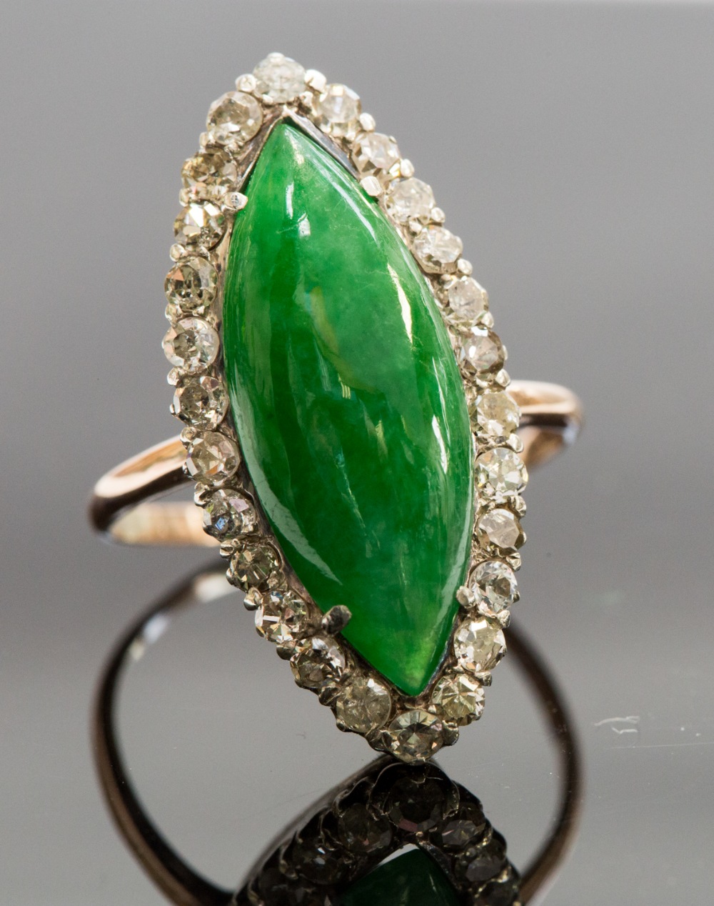 An Edwardian jadeite and diamond ring, set with a marquise jadeite cabachon, surrounded by diamonds,