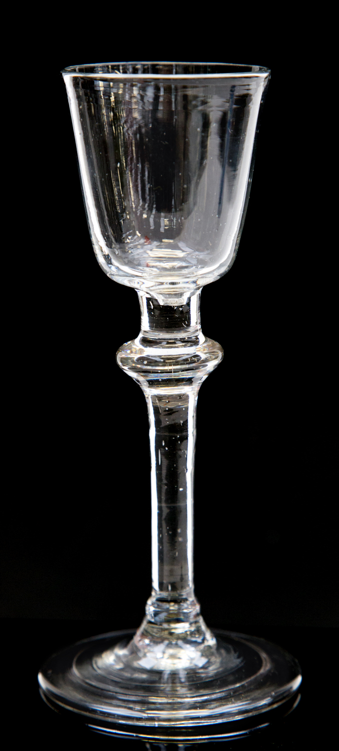 An 18th century wine glass, the round funnel bowl on a cushion knopped stem with angular inverted