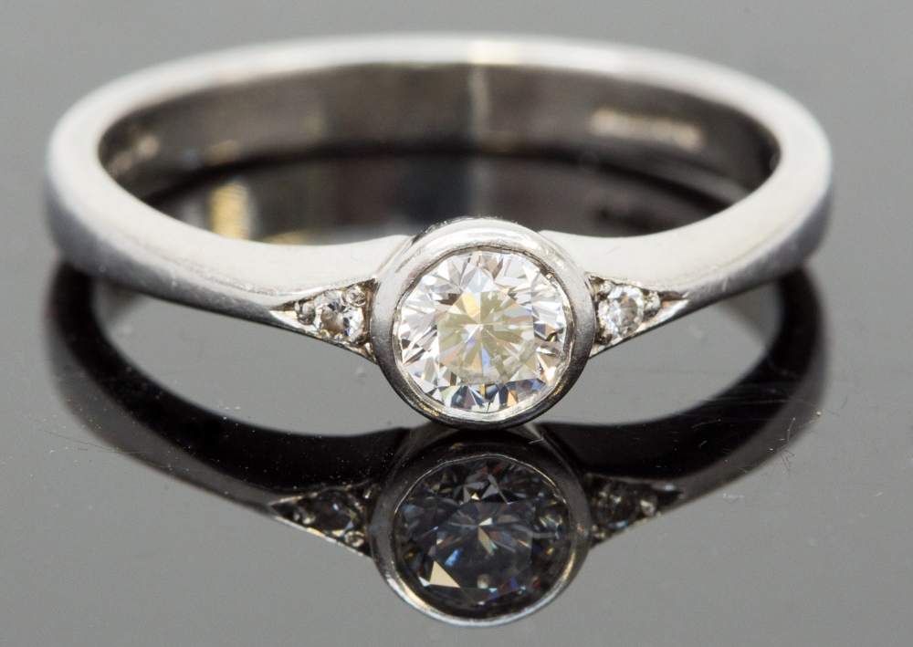 A platinum and diamond solitaire ring, the round cut brilliant stone approx 0.3ct, with two stones