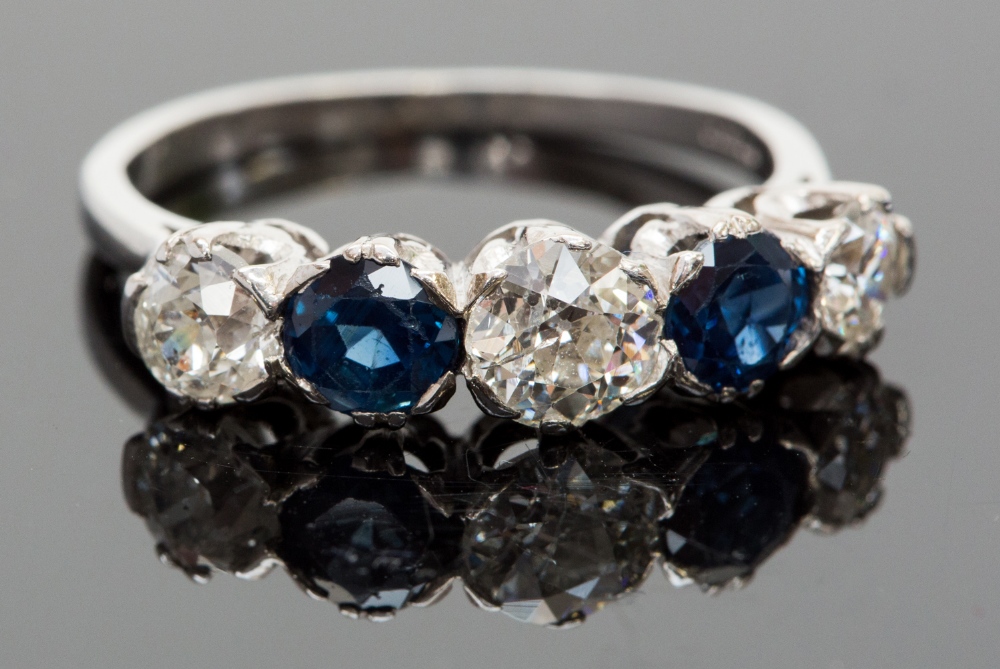 A platinum, sapphire and diamond five-stone ring, set with three diamonds divided by two sapphires,