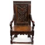 A mid 17th century oak wainscot chair, the crest rail with carved arcading, the back panel carved