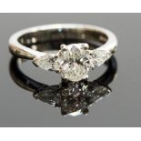 A platinum and diamond three-stone ring, the central oval stone approx 0.75ct, flanked by two