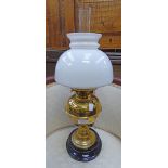 An old lamp, placed on black marble plinth, brass body with opaque white globe, glass funnel