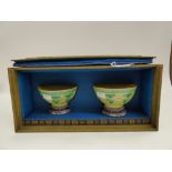 A green silk covered box containing two green and yellow glazed porcelain bowls,