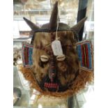 A tribal mask headdress, of cloth construction decorated with coloured beads, the face with fur