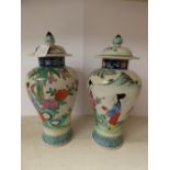 A pair of late 19th/early 20th Century Chinese famille rose vases with covers, female figures in