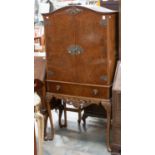 A mid 20th century walnut veneered cocktail cabinet, fitted with two doors and a single drawer,