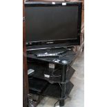 A contemporary black corner TV stand, three tier form, together with a flatscreen TV