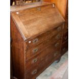 A George III oak bureau, circa 1790, the fall front opening to reveal drawers, pigeon holes and a