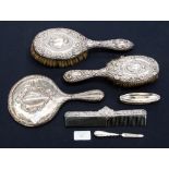 A collection of silver dressing table brushes and mirrors, ebonised with foliate scrolls, various