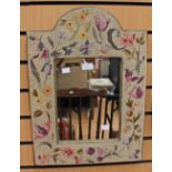 A wall mirror set in a tapestry woolwork frame