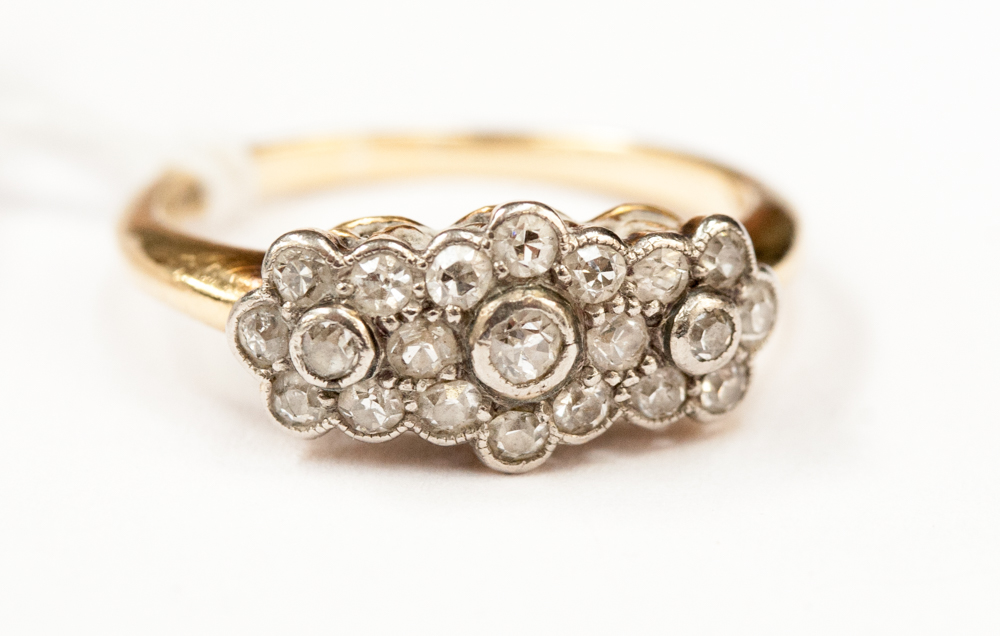 An Edwardian diamond cluster ring, having three central old cut stones,