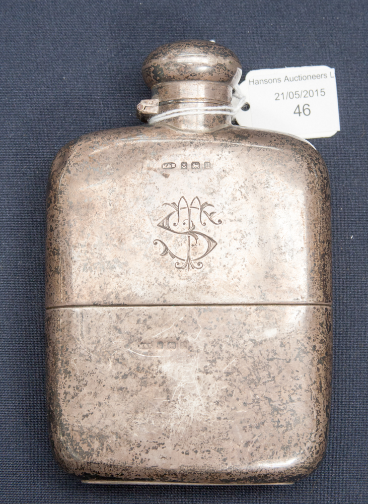 An early 20th Century silver hip flask and hinged cover, monogrammed with silver sleeve,