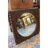 A George V 17th Century style oak wall mirror fitted with bevelled edge glass.