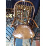 An ash and elm Windsor armchair, with a hooped back, saddle seat and raised on turned legs,