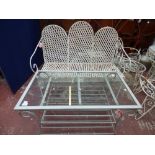 A white painted wrought iron garden bench together with a glass topped coffee table,