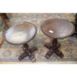 A pair of oak wine tables, each with a circular top raised on a turned column and cross support,