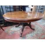 A late Victorian walnut quarter veneered loo table, the oval top raised on four turned columns,