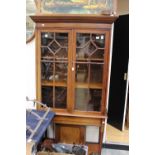 An Edwardian mahogany display cabinet fitted with two glazed doors over a single panel door,